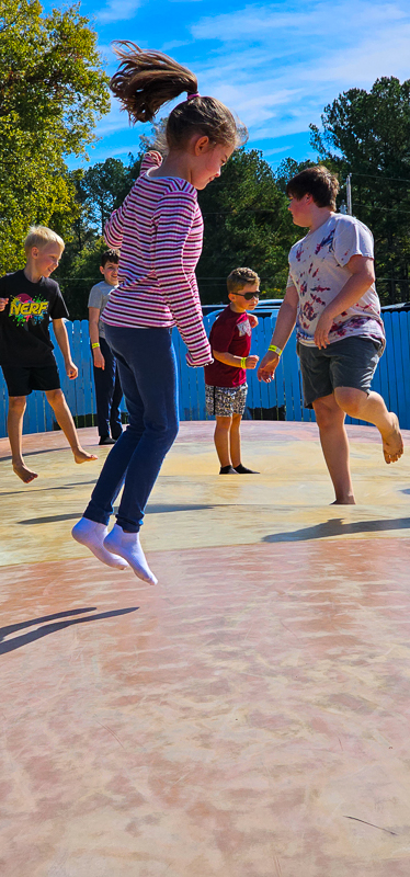 A student mid-jump on the playground with friends around her