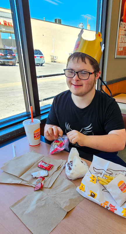 A student wearing a paper crown at a restaurant table during an outing