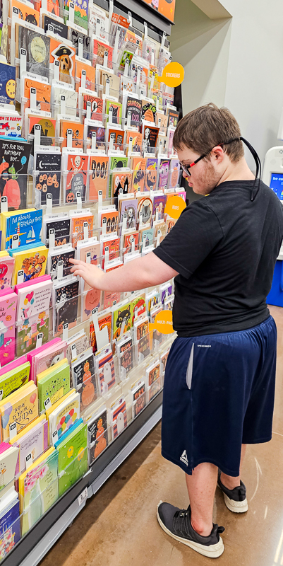 An older student choosing a card from a rack on a trip off campus