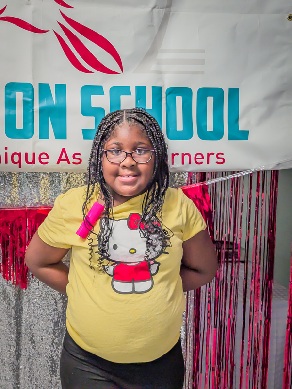 A student smiling in front of The Edison School banner at a school event