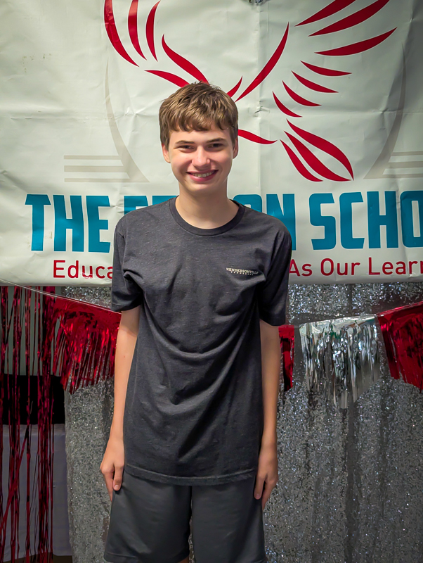 A student standing in front of The Edison School banner