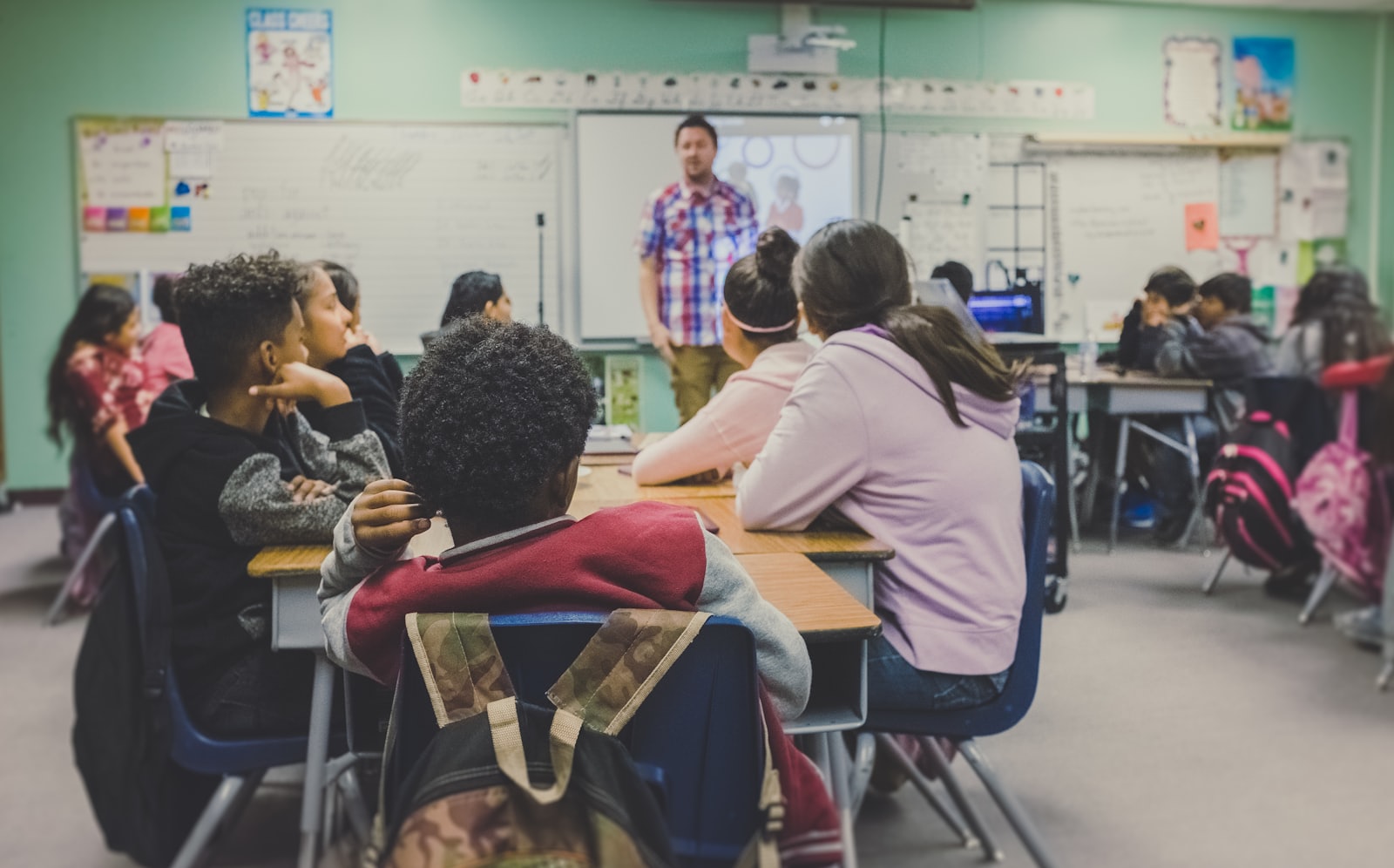 A teacher at the front of a small classroom with students working at their desks