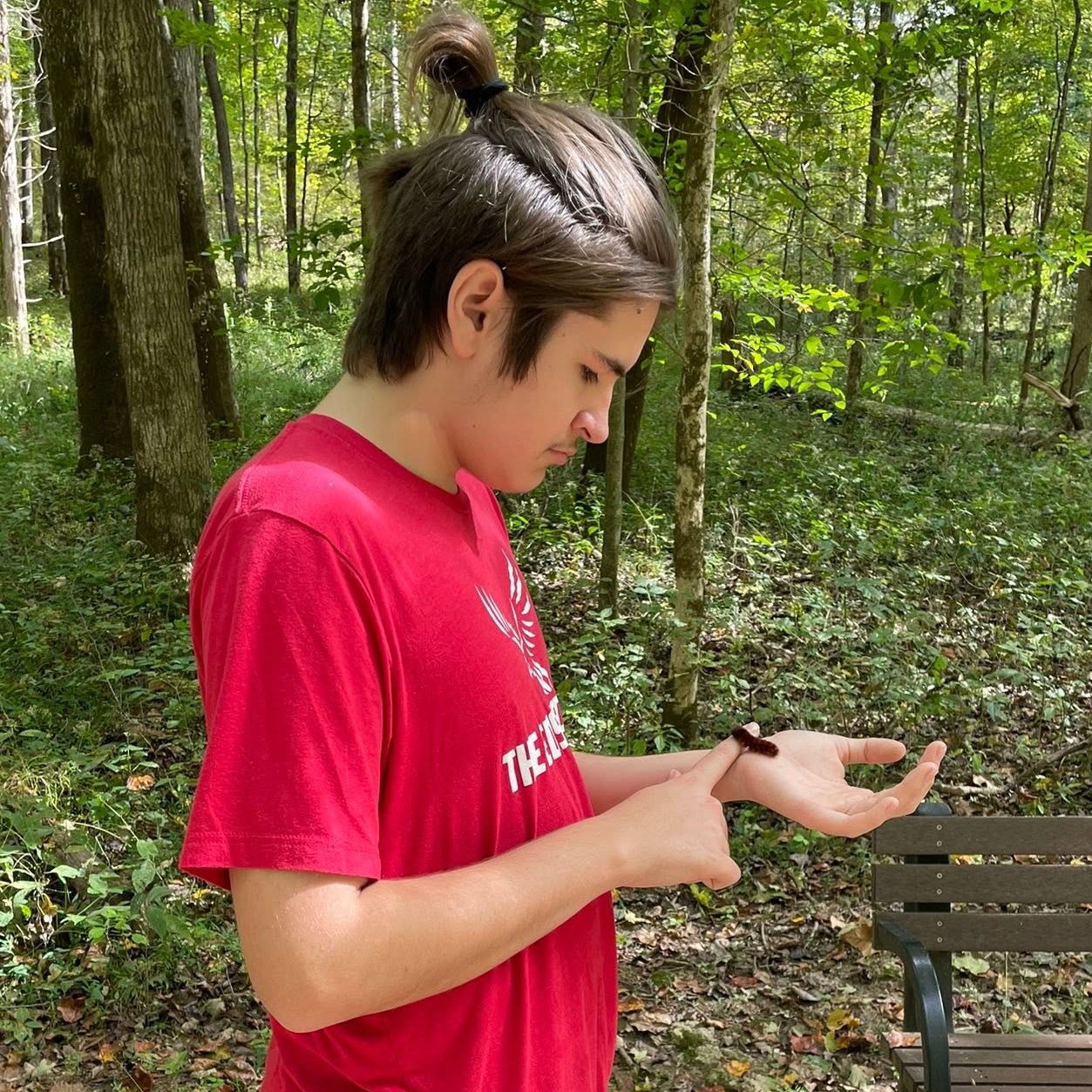 Gabe outdoors on a school trip, a caterpillar resting on his hand