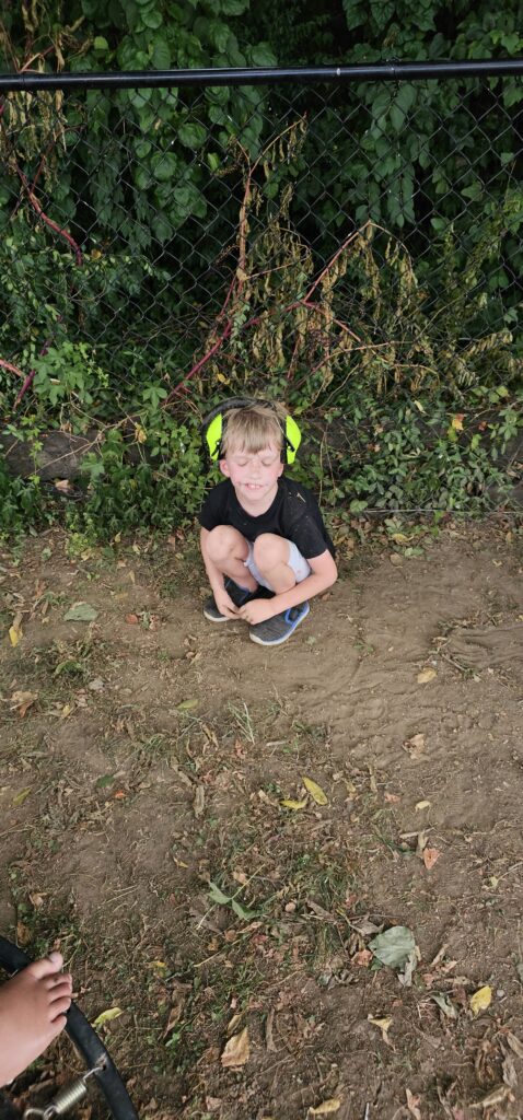 A student crouched down outdoors, taking a break during recess
