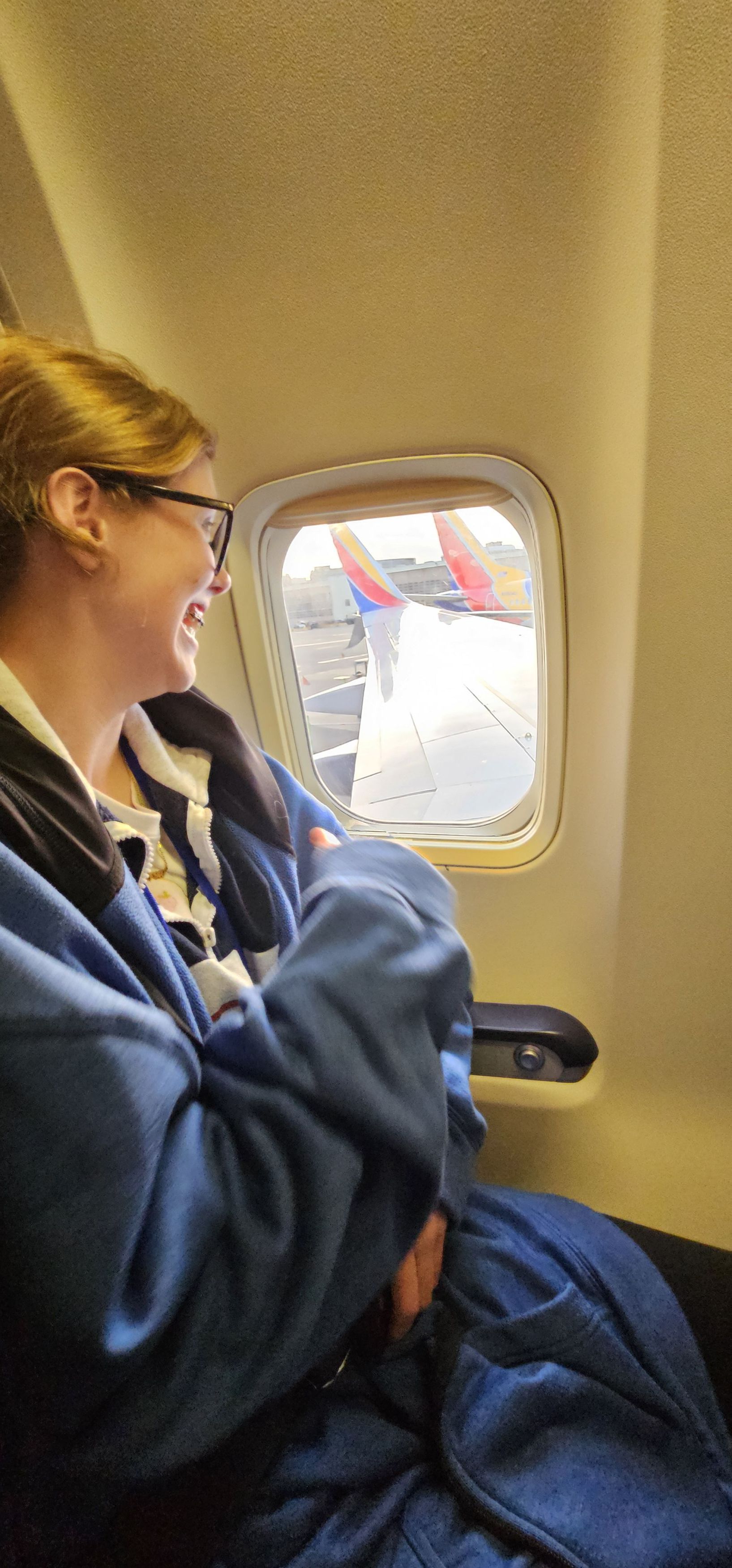 An Edison student smiling as she looks out of the window seat on the plane